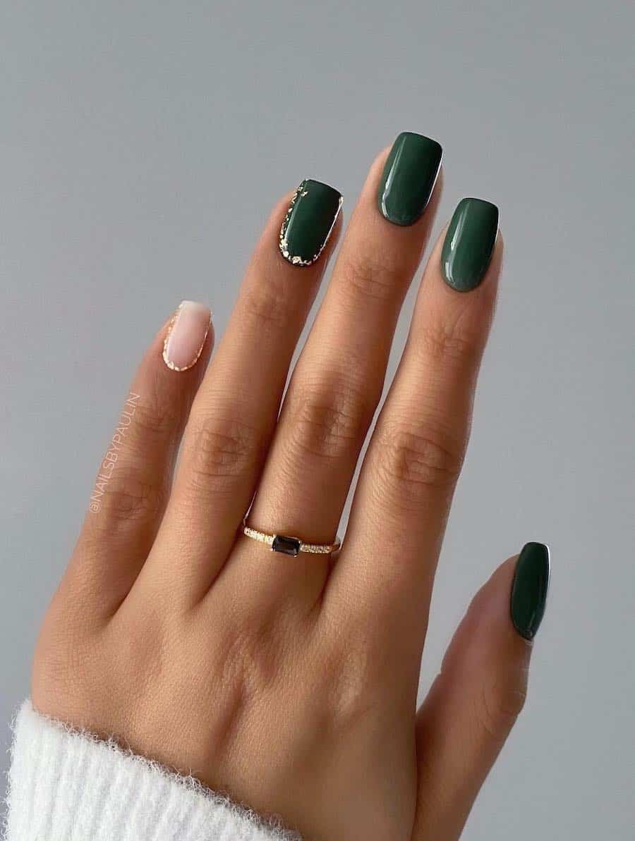 a hand with short squoval nails painted in a forest green color with one ɴuᴅᴇ accent nail and silver flakes details