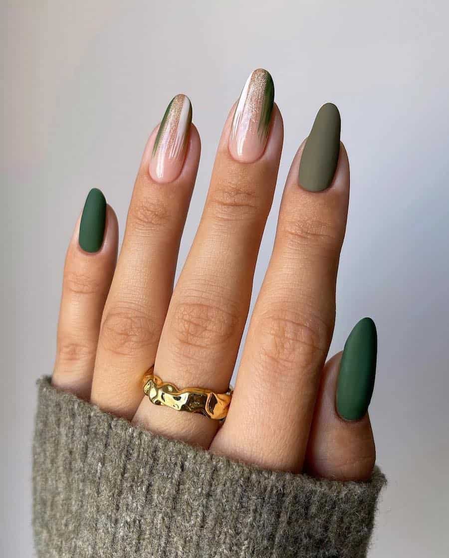 a hand with long almond nails painted in a combination of glossy ɴuᴅᴇ, matte olive green, and matte forest green polish with white and glitter accents